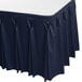 A navy blue Snap Drape table skirt with pleated edges on a table.