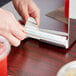 A person's hands wrapping a clear paper wrapper around a plastic straw.