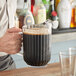 A man pouring a drink into a Cambro plastic pitcher.