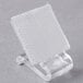 A clear plastic clip with a white square on a clear plastic holder.