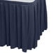 A navy blue Snap Drape table skirt with pleated edges on a table.