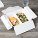 A white Eco-Products compostable takeout container with a sandwich and salad inside.