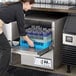 A woman putting glasses in a Jackson Undercounter Dishwasher on a counter in a professional kitchen.