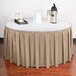 A table with a beige box pleat table skirt on a table with a tray of drinks.