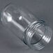 A clear glass globe for a light bulb on a gray surface.