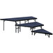 A National Public Seating portable stage pie unit with blue carpet on a table with a blue top.
