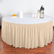 A table with a Snap Drape cream shirred pleat table skirt with a bowl of oranges and a thermos.