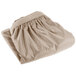 A folded beige table skirt on a white background.