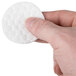 A person holding a round white Basic Earth Botanicals disc with a hole in it.