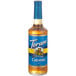 A close up of a Torani Sugar-Free Caramel Flavoring Syrup 750 mL glass bottle with a blue label.