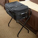 A black suitcase on a black CSL metal luggage rack stand.