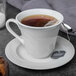 A Libbey Royal Rideau white porcelain tea saucer with a cup of tea on it.