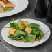 A Libbey Royal Rideau white porcelain plate with a salad of spinach, croutons, and vegetables.