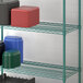 A Regency green wire shelf with plastic containers holding black and red plastic boxes.