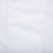 A close up of a white Chef Revival long sleeve chef jacket with a button and mesh back.