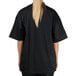 A woman wearing a black short sleeve Chef Revival chef jacket with mesh back.