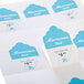 A stack of tea bags with scalloped edge white labels with blue cloud shaped logos.