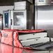 A stack of pizza boxes in a red Rubbermaid insulated delivery bag.