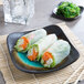 A Libbey stoneware plate with a roll of vegetables and rice and a bowl of green seaweed.
