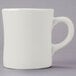 A close-up of a Tuxton eggshell white mug with a handle.
