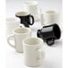 A close-up of a white Tuxton diner mug with a black rim and handle.