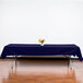 A table with a navy blue Intedge rectangular tablecloth and a vase of flowers.