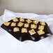 A black GET Stone-Mel display tray with a plate of food and crackers on a table.