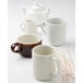 a white teapot and a cup