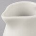 A Tuxton Eggshell China creamer with a handle.