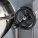 A black hand wheel on a Avantco mixer with a white background.