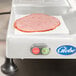 A Globe meat slicer slicing a piece of ham.