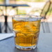 A clear GET Bahama plastic tumbler filled with ice tea on a table outside.