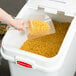 A hand using a Rubbermaid plastic scoop to pour pasta into a Rubbermaid plastic container.