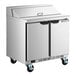 A stainless steel two-door refrigerated sandwich prep table on wheels.