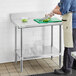 A man cutting vegetables on a Regency stainless steel work table with undershelf.