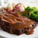 A plate of meat with Vanee Roasted Beef Gravy, broccoli, and a side of vegetables.