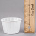 A white Solo paper souffle cup next to a ruler.