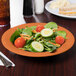 A plate of salad with vegetables and a spoon on a table.