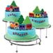 A Wilton three-tiered display stand with train themed birthday cakes on it.