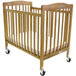 A close-up of a wooden L.A. Baby folding crib with wheels.