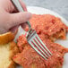 A hand holding a Bon Chef Manhattan stainless steel dinner fork over a plate of food.