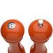 Two Chef Specialties orange pepper mills with a salt shaker on top.