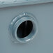 A close-up of a hole in a metal surface with gray threaded connections.