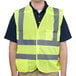 A man wearing a Cordova lime high visibility safety vest over a black shirt.