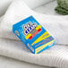 A blue box of OxiClean powder on a white towel.
