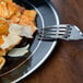 A Fineline Black Plastic plate with silver bands holding pasta with a fork.