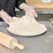 A person in gloves holding dough on an American Metalcraft Super Perforated Pizza Pan.