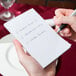 A person writing on a white Choice scratch pad with a pen.