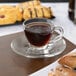 A Libbey glass espresso cup of coffee on a plate next to pastries.