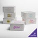 A group of white customizable cake boxes with different text colors.